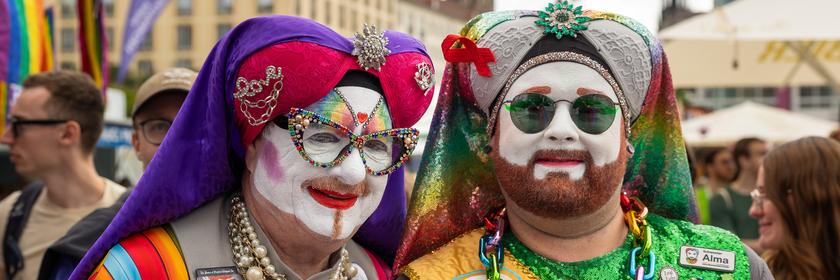 In Dresden stehen Teilnehmer des Straßenumzugs zum Christopher Street Day posierend auf dem Altmarkt für ein Foto. Ihre Gesichter sind weiß geschminkt und sie tragen bunte Kostüme.