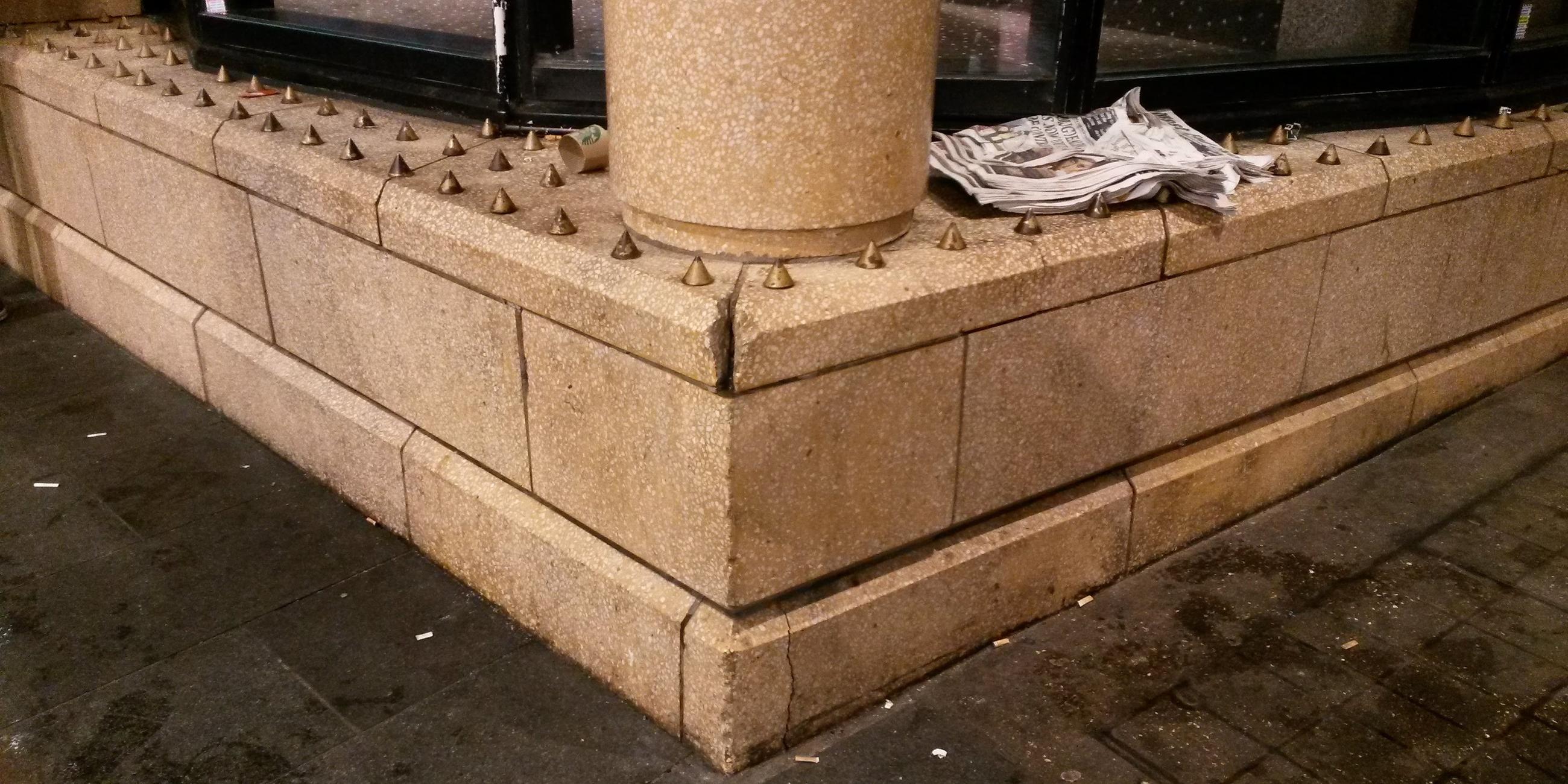 Eine Ecke von einem Gebäude in London, auf der viele kleine Metallspitzen angebracht sind. 