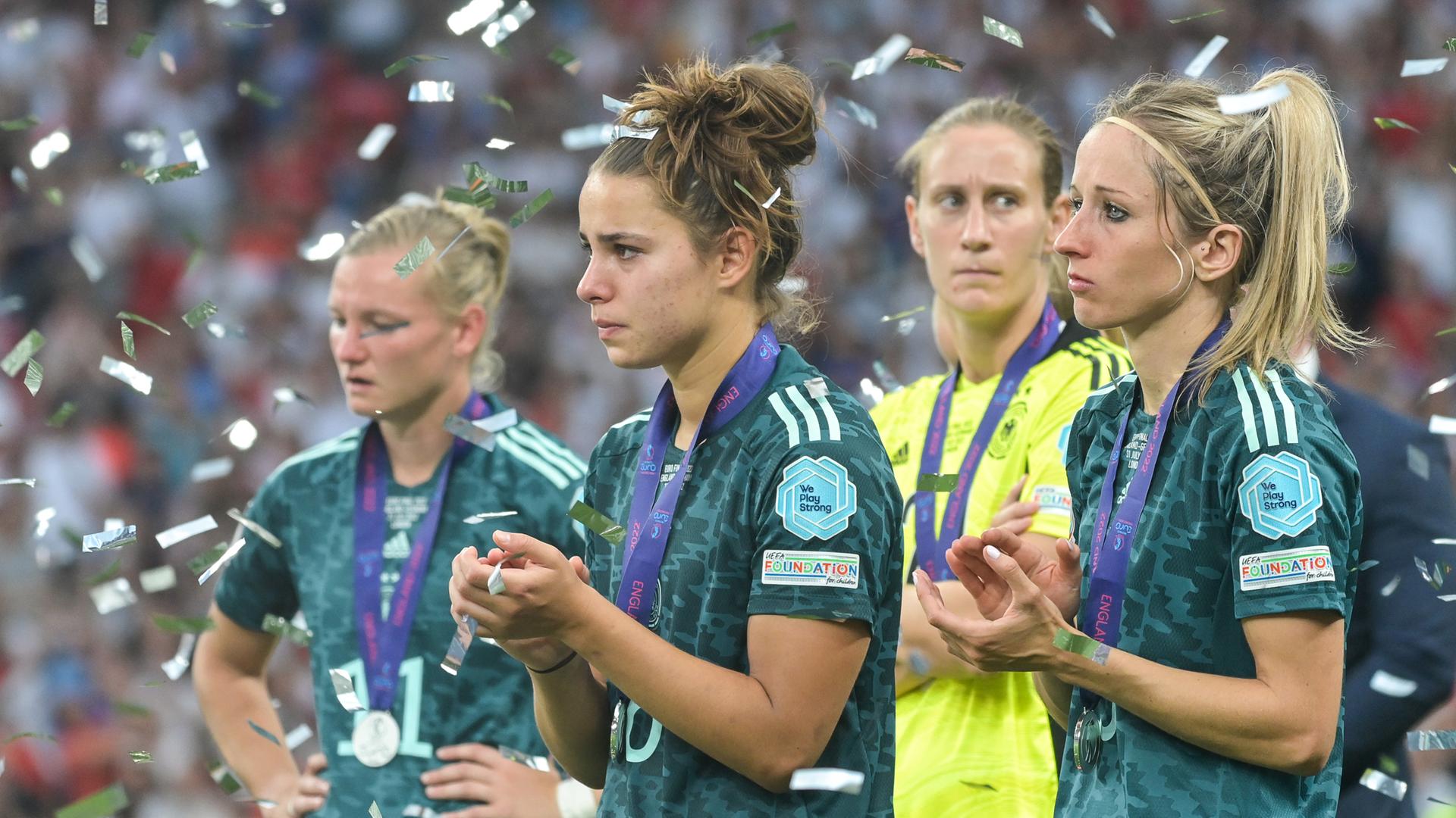 Deutschlands Alexandra Popp (l-r), Lena Sophie Oberdorf, Torhüterin Ann-Katrin Berger und Kathrin Hendrich stehen im Konfettiregen für die Engländerinnen.