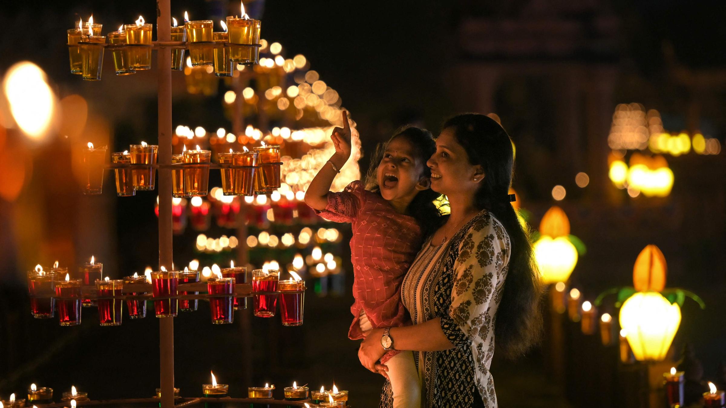 Eine Frau und ein Mädchen bestaunen Öllampen an einem Tempel.