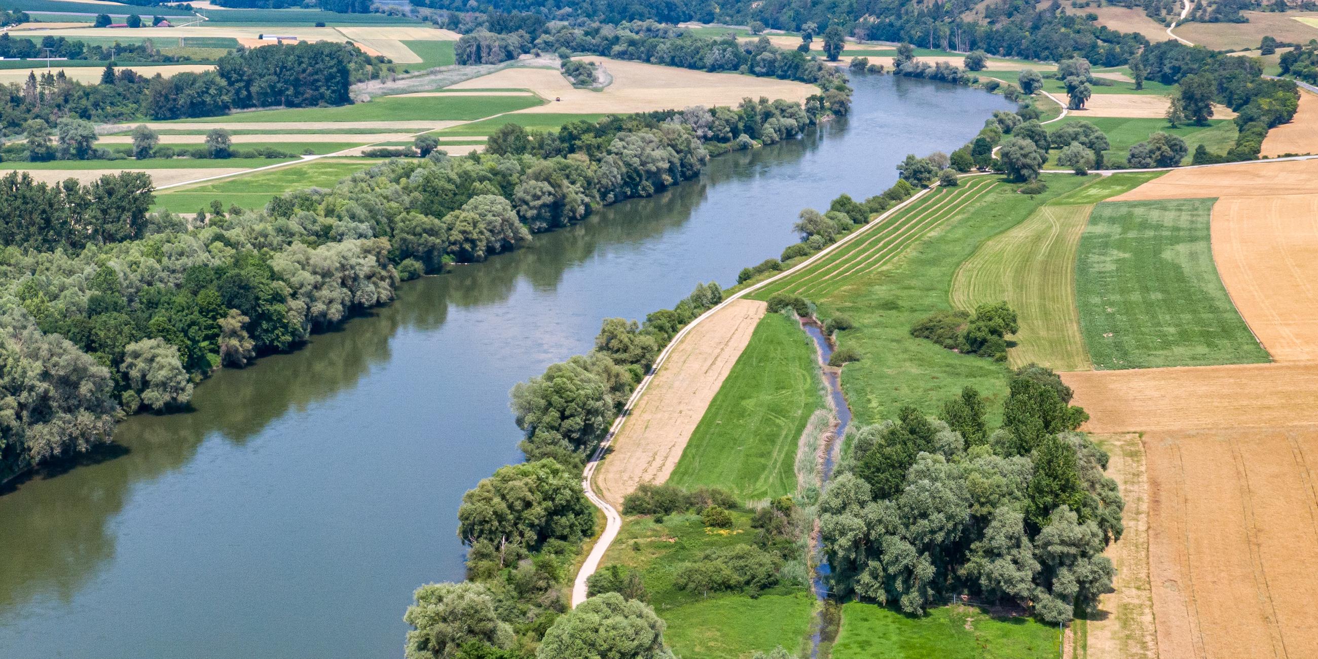 Ein Fluss schlängelt sich zwischen Feldern in der Landschaft hindruch. 