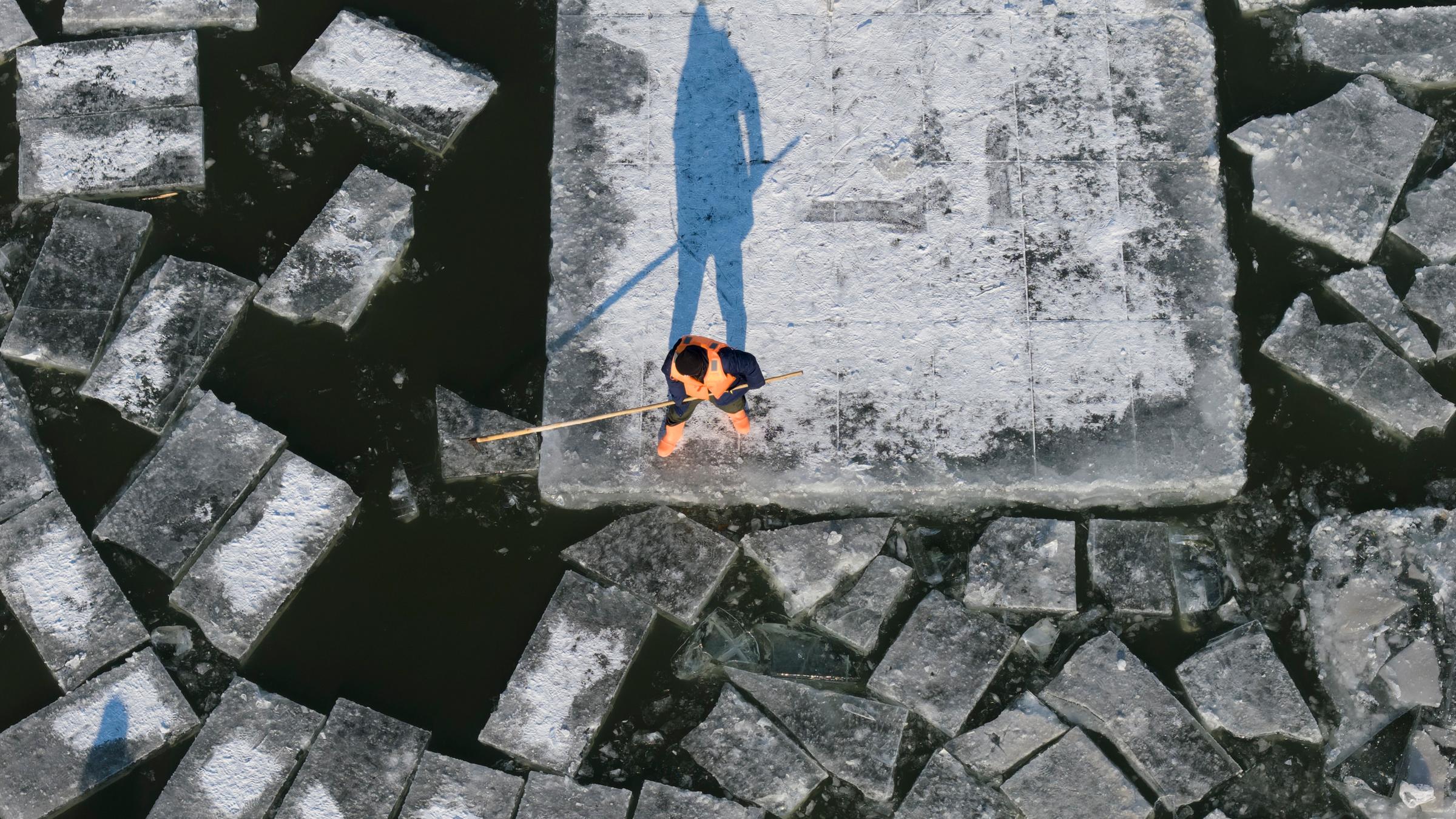 Ein Luftbild einer Drohne zeigt einen Arbeiter, der im Harbiner Abschnitt des Songhua-Flusses in Harbin in der nordostchinesischen Provinz Heilongjiang Eis schneidet.