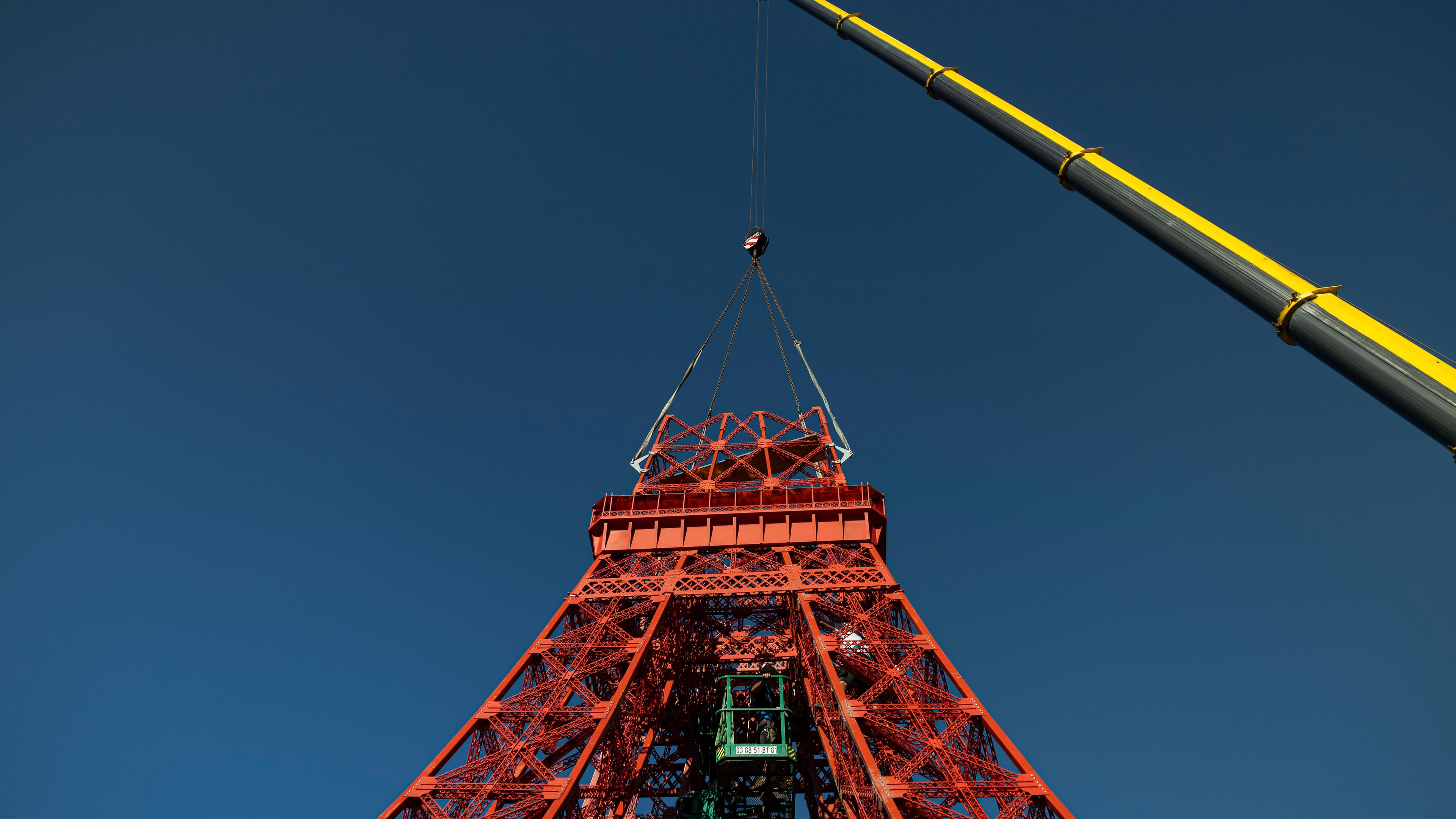 Bauteile werden mit einem Kran auf die Spitze des zweiten Eiffelturms gesetzt.