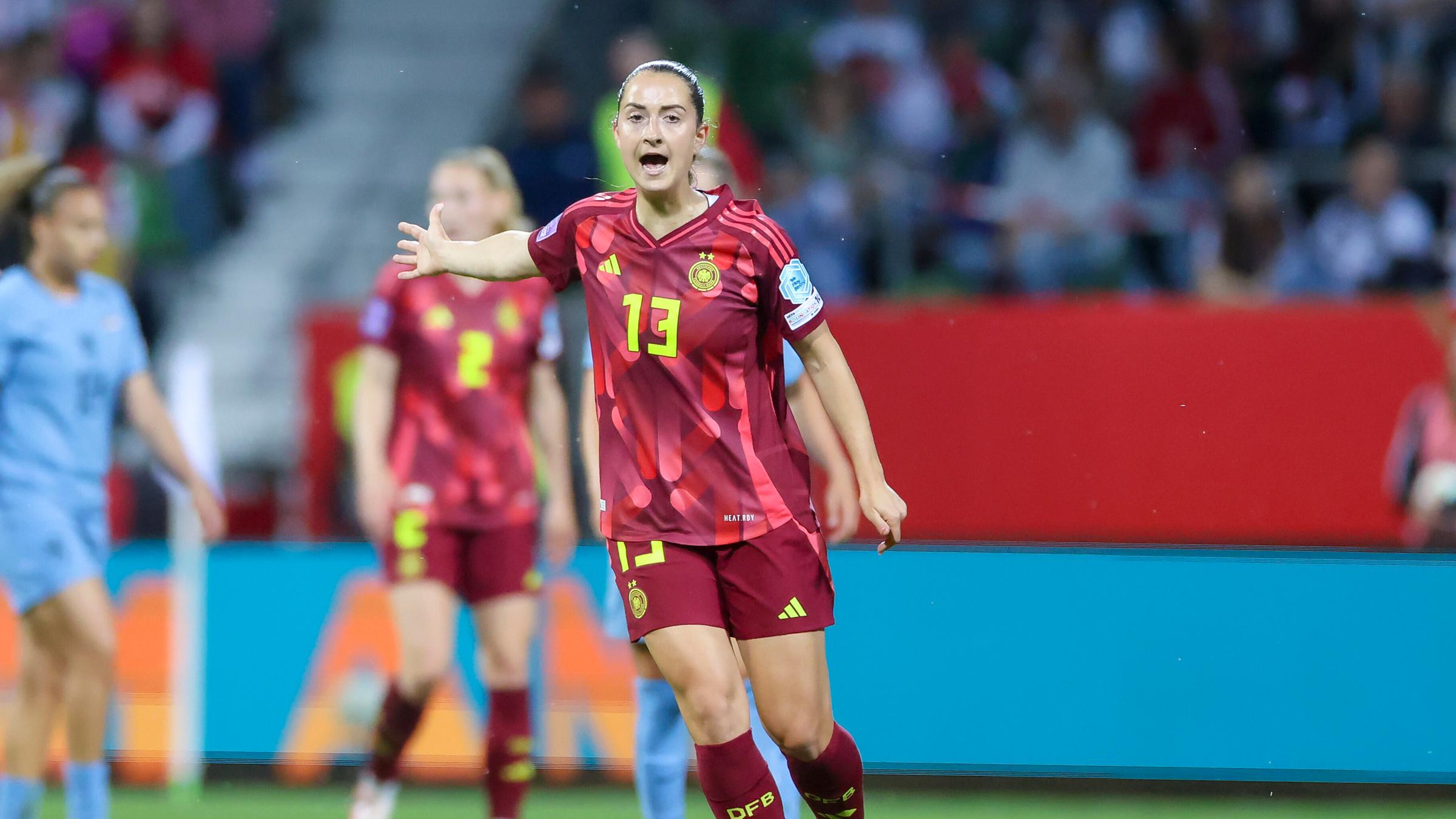 Sara Daebritz trägt ein rotes Trikot und gestikuliert auf dem Fußballplatz