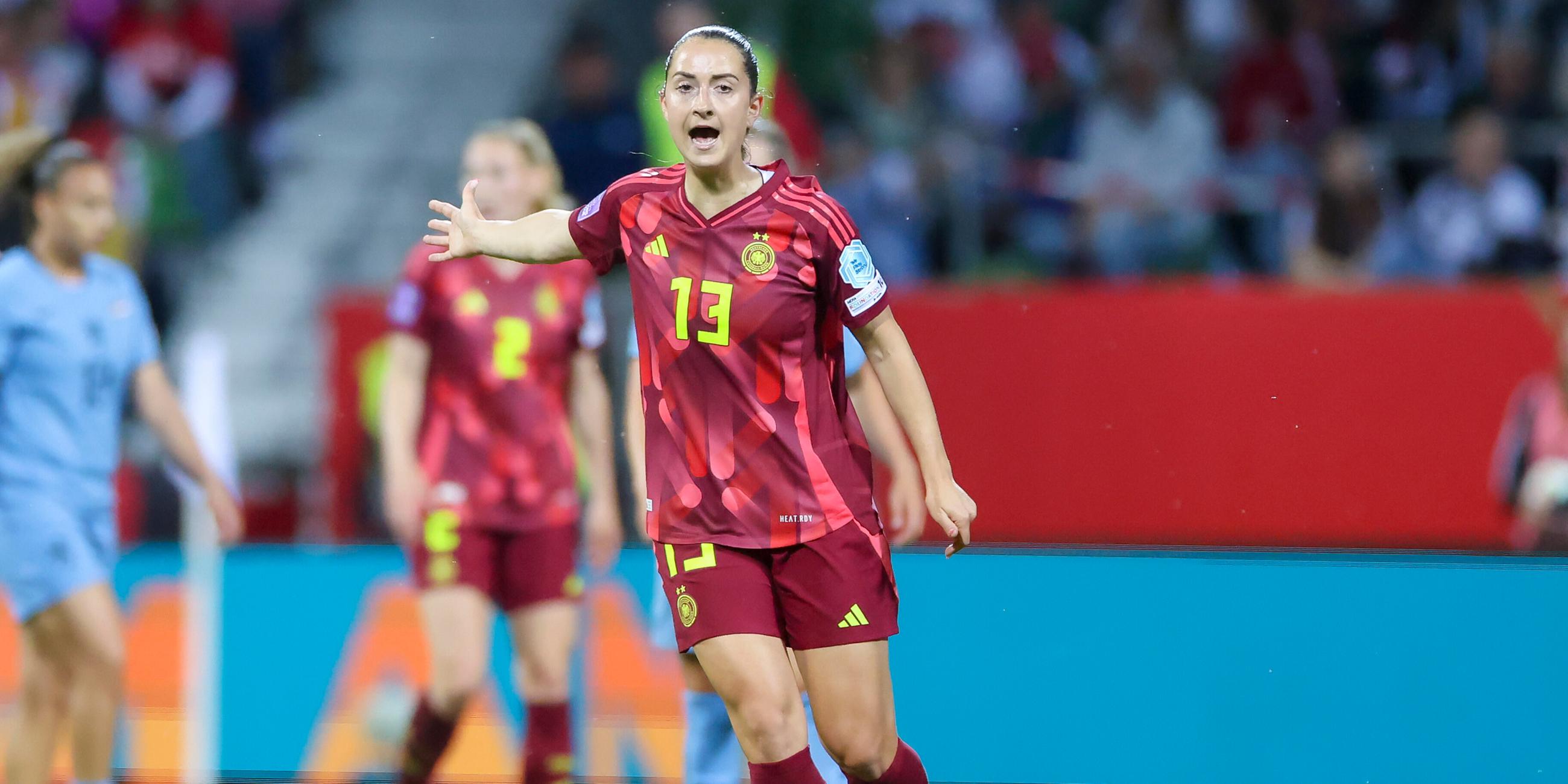 Sara Daebritz trägt ein rotes Trikot und gestikuliert auf dem Fußballplatz