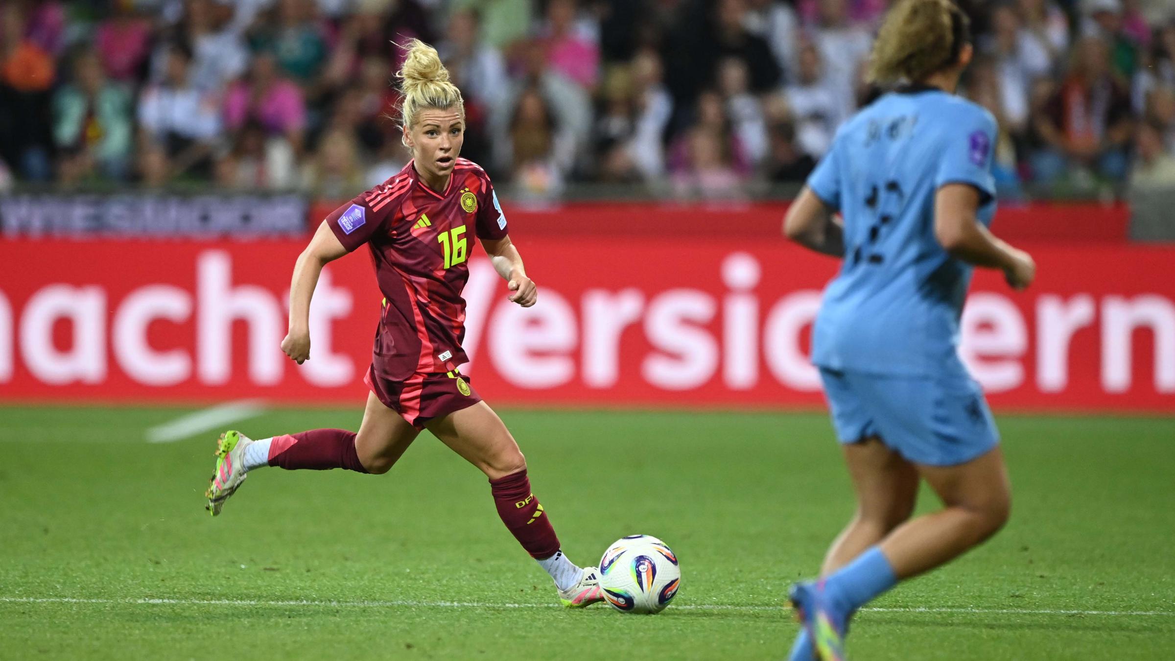 Linda Dallmann rennt mit dem Ball und schaut zu einer Gegnerin rüber auf dem Fußballplatz