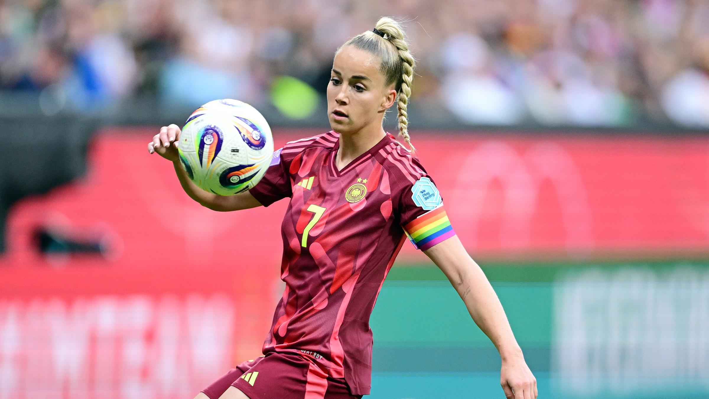 Giulia Gwinn schaut auf den Ball auf Augenhöhe, sie trägt ein rotes Trikot und eine Regenbogenbinde am Arm