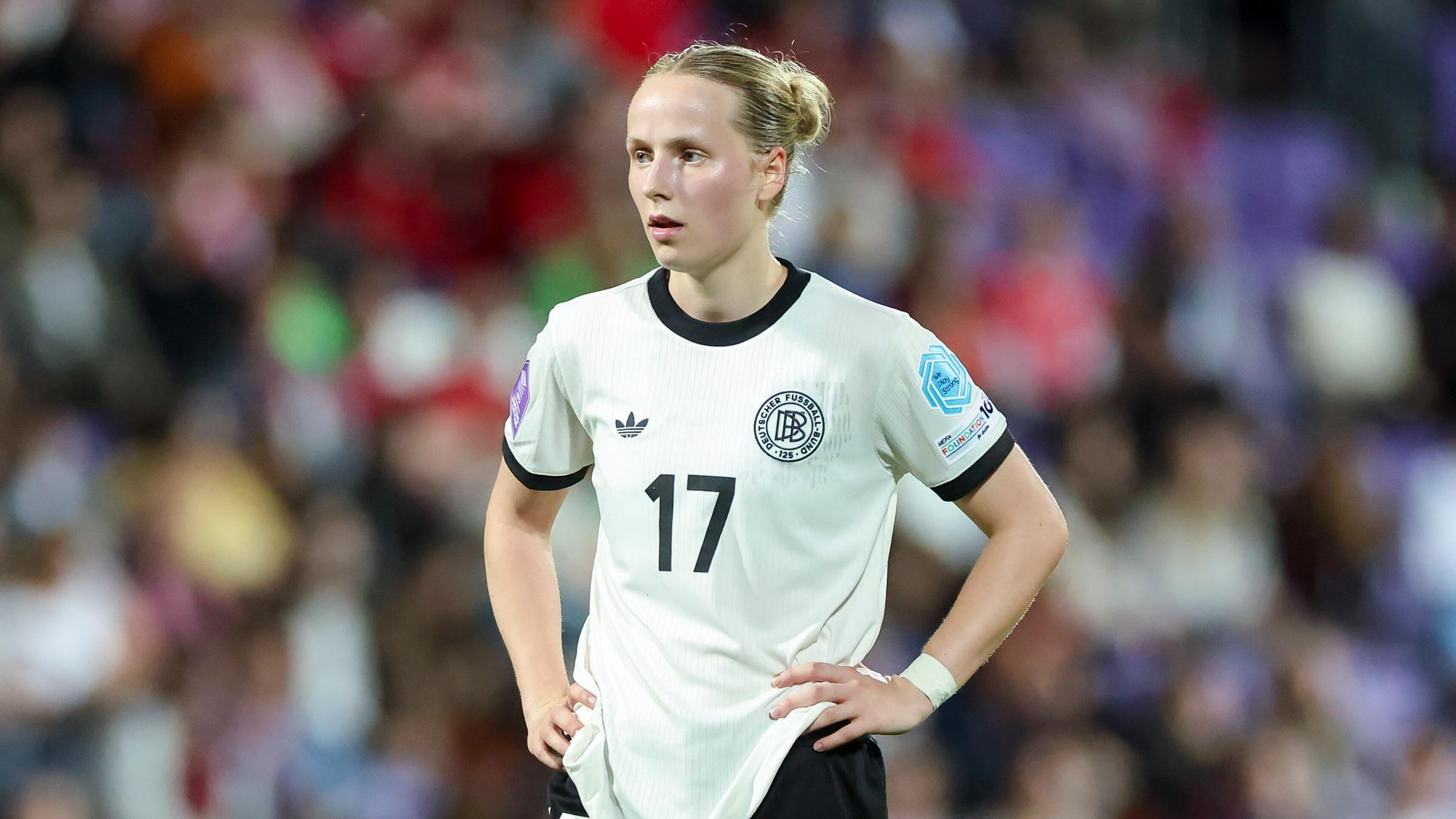 Franziska Kett hat die Arme in die Seite gestemmt und blickt nach vorne auf dem Fußballplatz