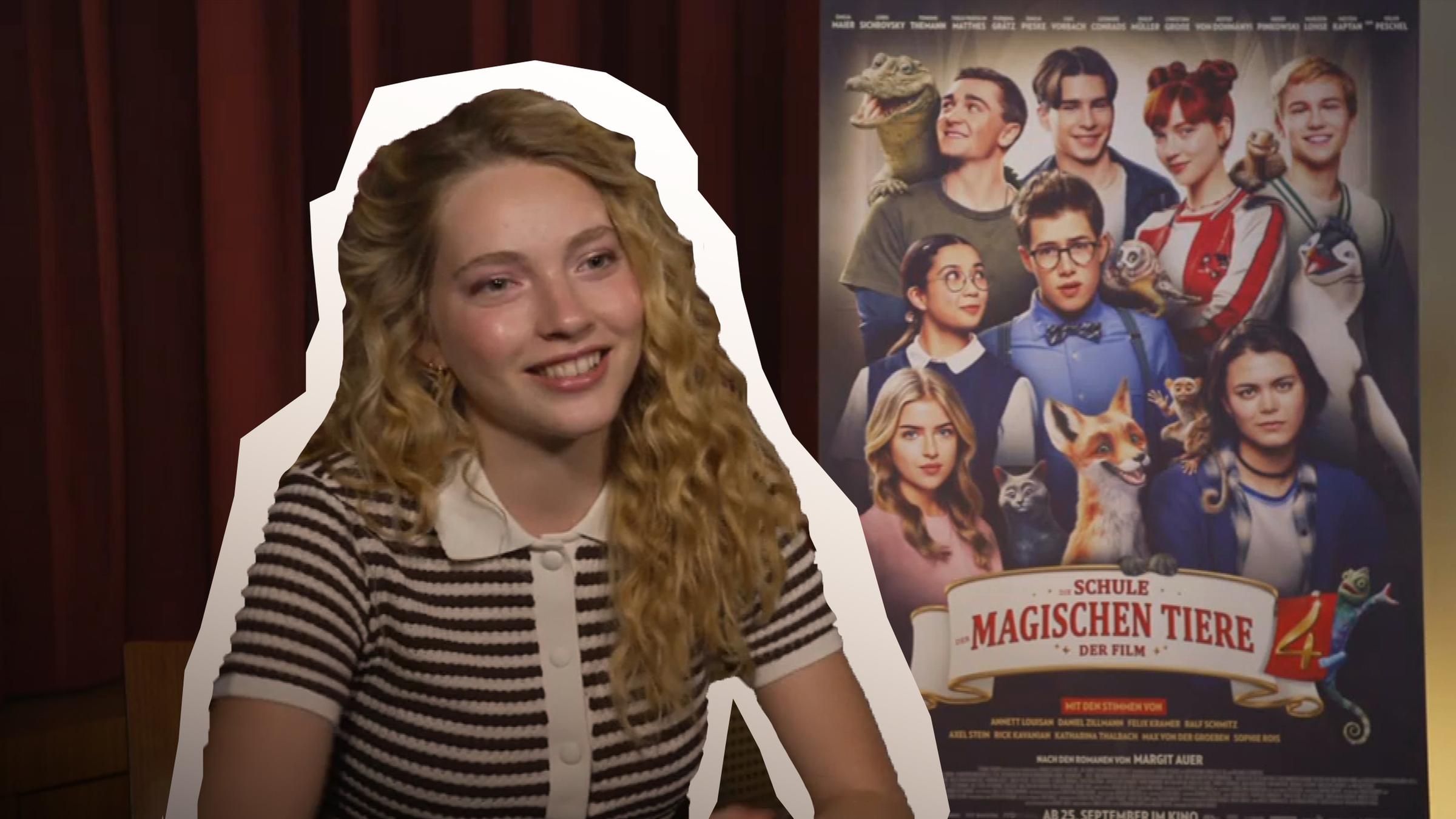 Schauspielerin Emilia Maier neben ihr das Plakat des neuen Kinofilms "Die Schule der magischen Tiere 4".