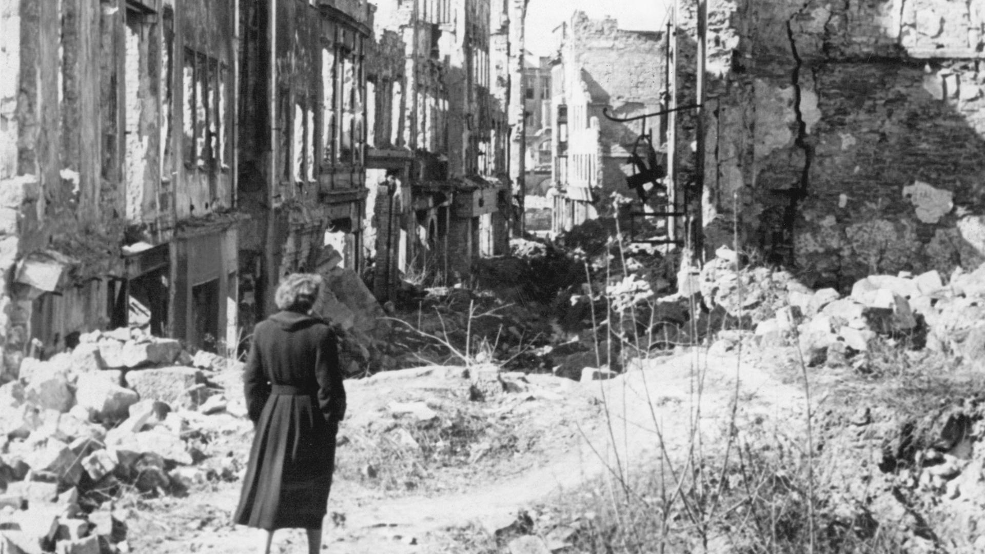 Eine Frau geht nach dem Ende des Zweiten Weltkriegs durch das zerstörte Deutschland.