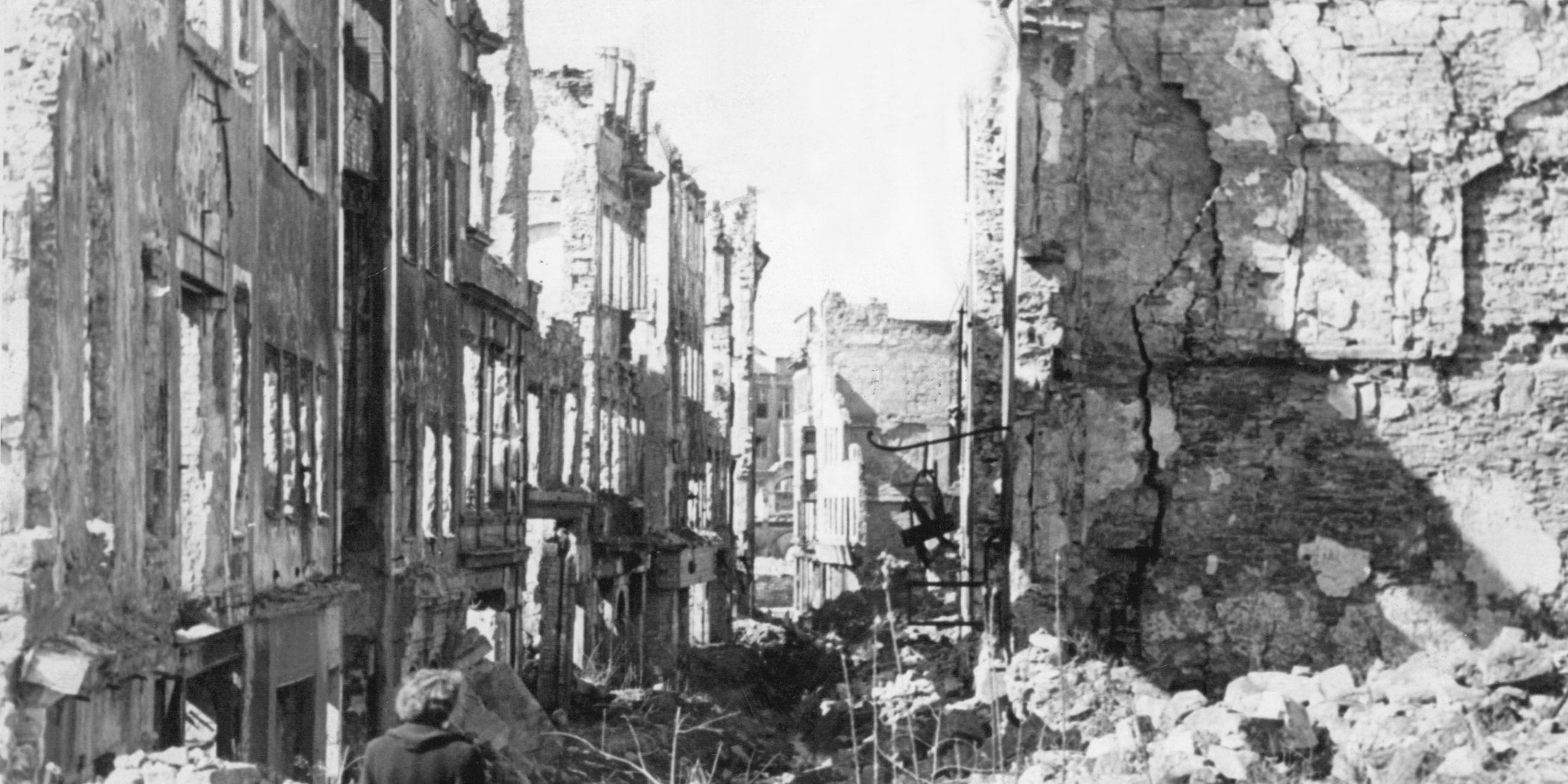 Eine Frau geht nach dem Ende des Zweiten Weltkriegs durch das zerstörte Deutschland.