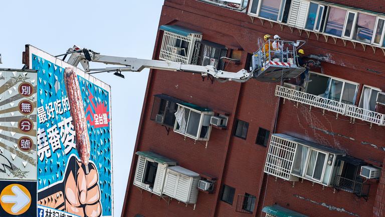 Ein Kran an einem sehr schiefen Haus nach dem Erdbeben in Taiwan