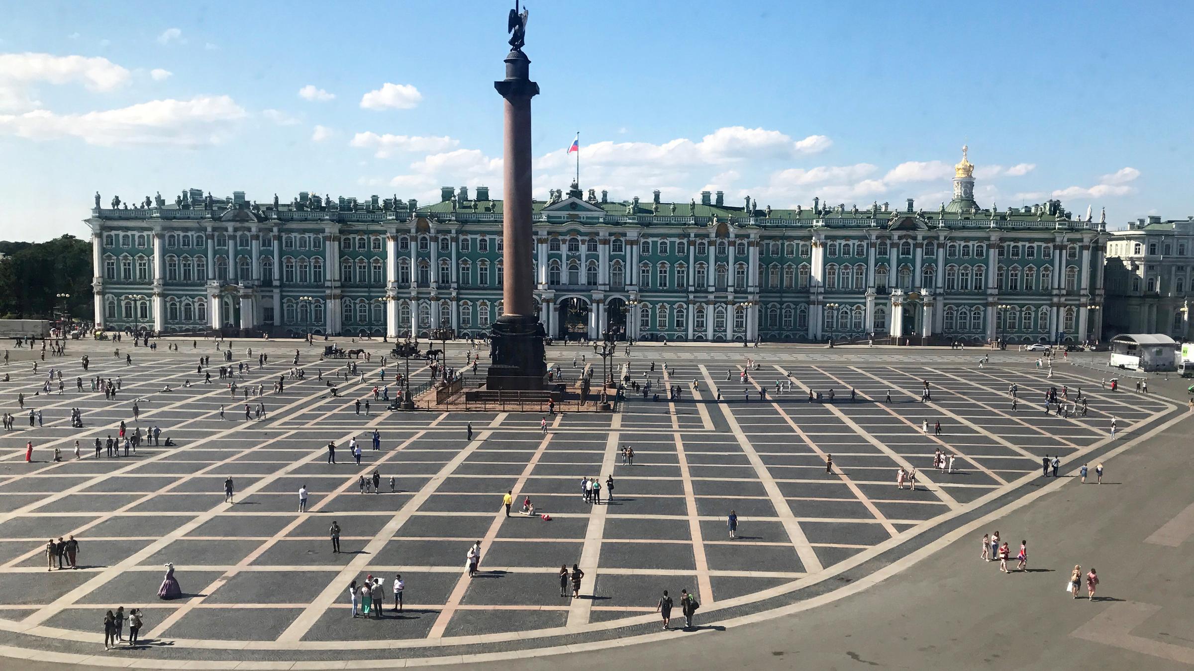 Man sieht das Kunstmusseum Eremitage und seinen Vorplatz, auf dem mehrere Menschen sind. 