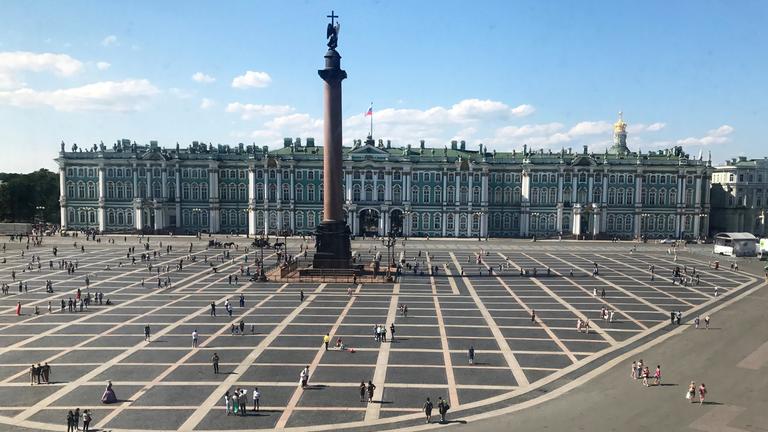 Man sieht das Kunstmusseum Eremitage und seinen Vorplatz, auf dem mehrere Menschen sind. 