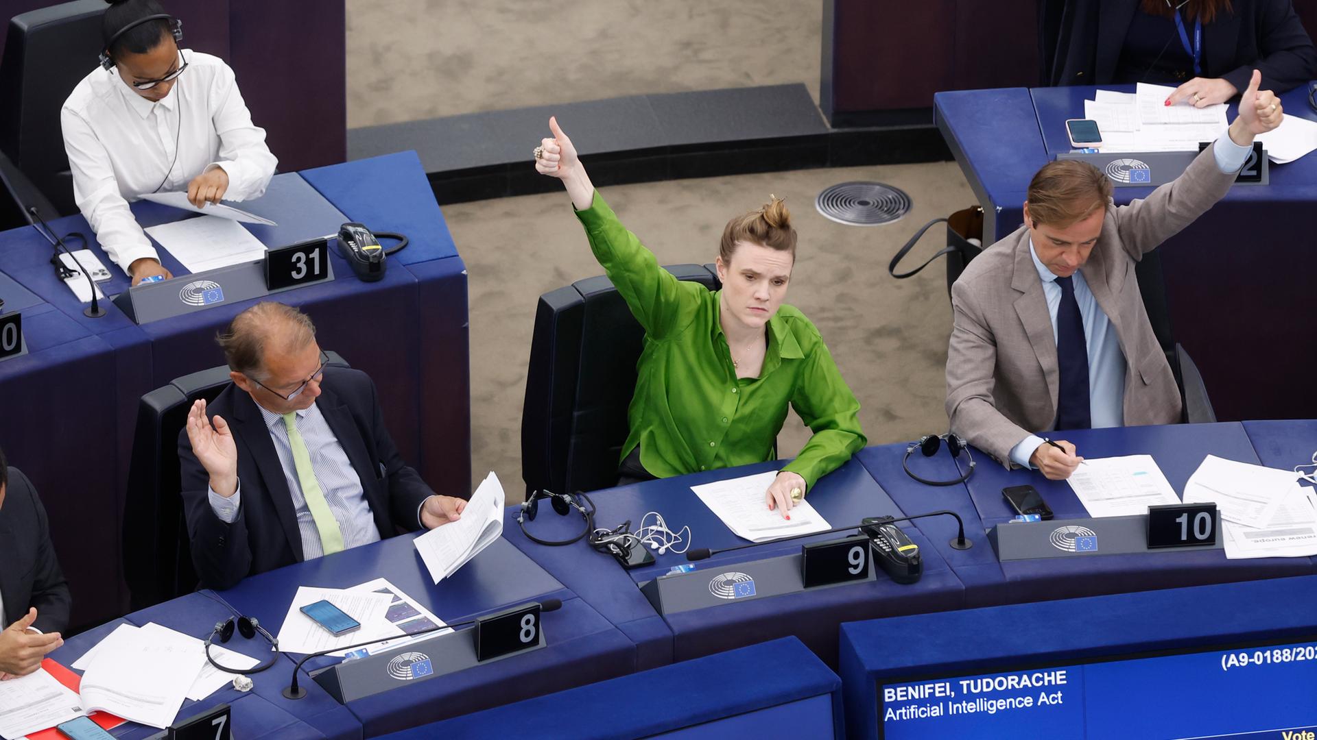 Politikerinnen und Politiker geben Handzeichen und stimmen ab