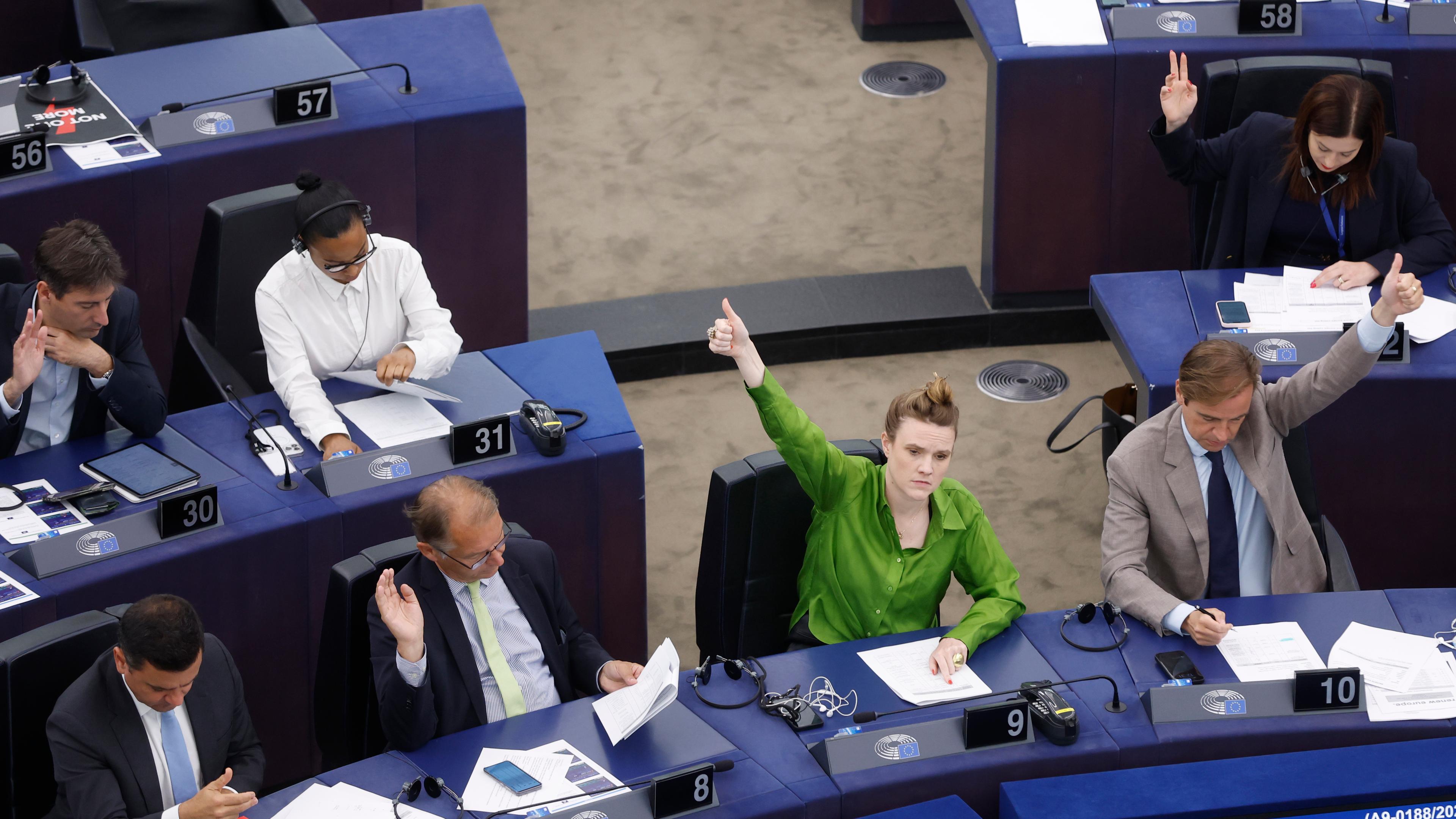 Politikerinnen und Politiker geben Handzeichen und stimmen ab