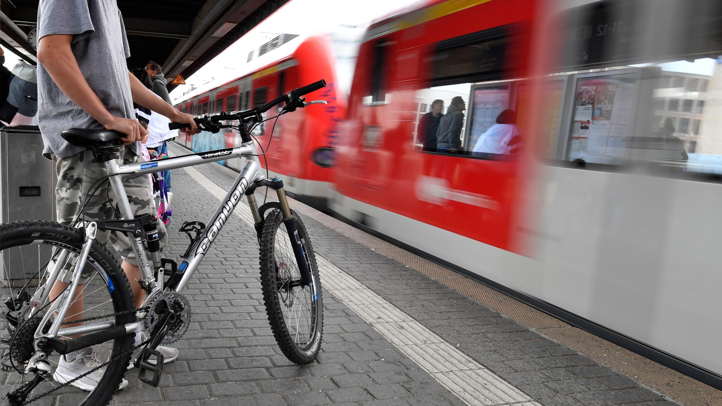 in Radfahrer wartet auf die Einfahrt eines Regionalzuges am Deuter Bahnhof.