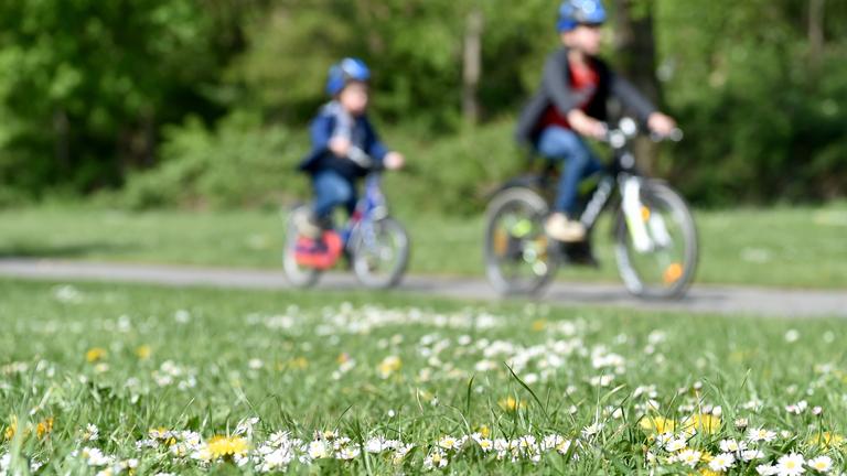 Zwei Kinder fahren Fahrrad im Grünen.