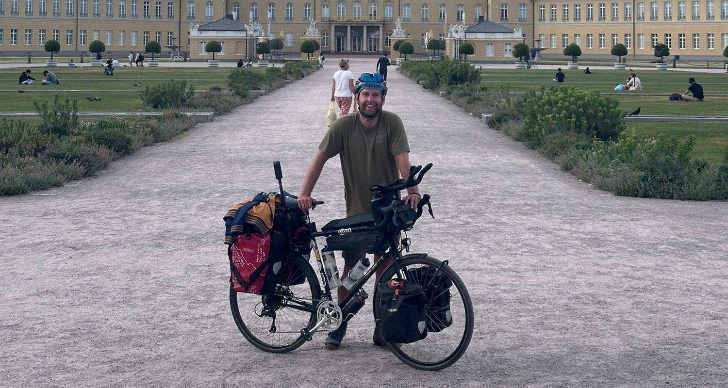 Ein Mann steht mit seinem Fahrrad vor einem Gebäude