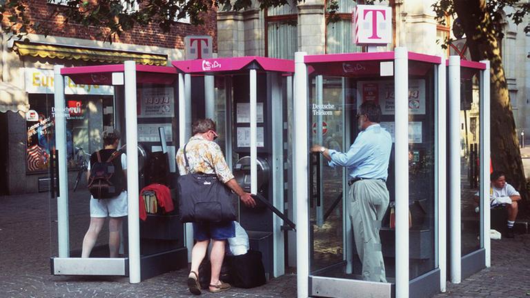 Vier Telefonzellen mit telefonierenden Menschen. 