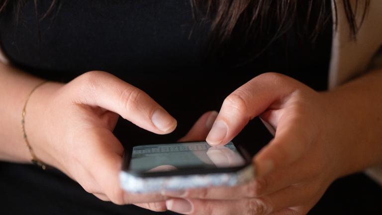 Jugendliche tippt auf einem Smartphone.