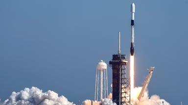 Eine Rakete startet, dahinter blauer Himmel