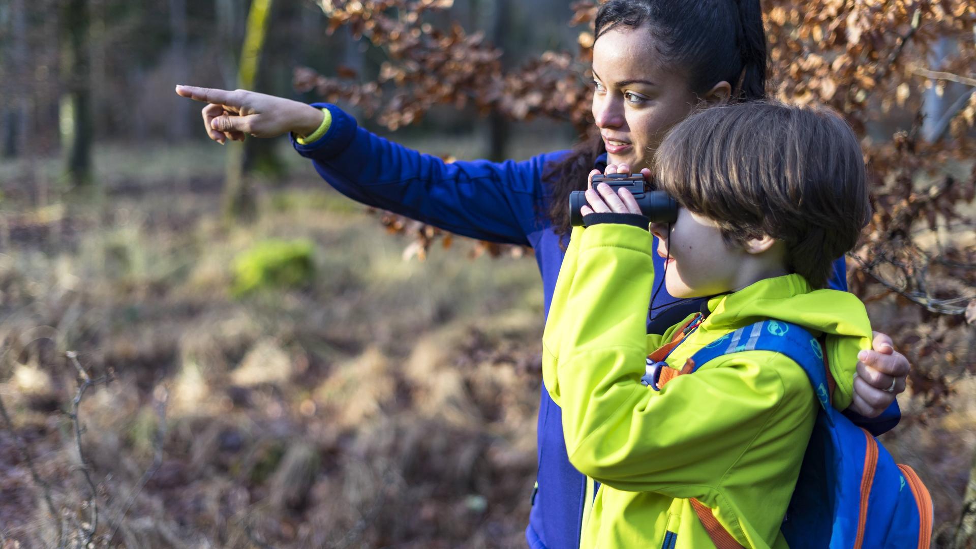 Mutter und Kind beobachten mit einem Fernglas die Vögel
