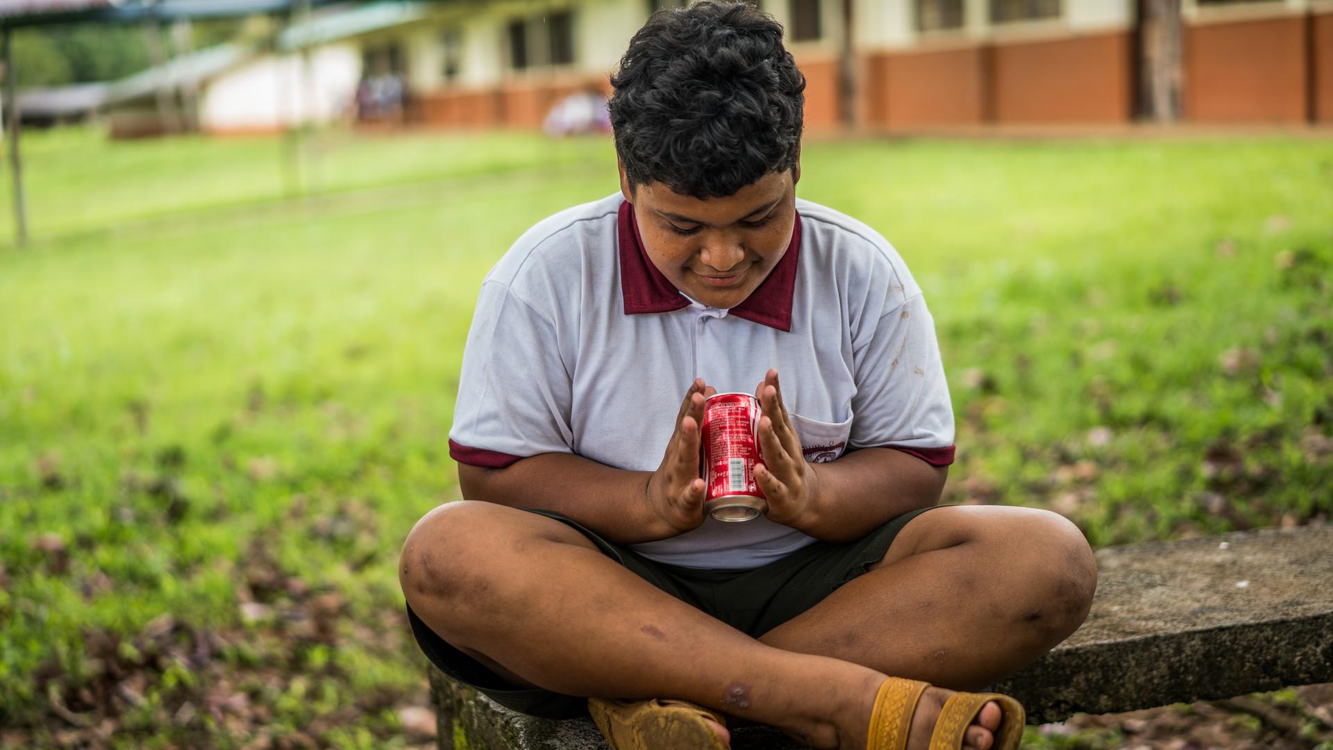 Ein übergewichtiger Junge hat eine Cola-Dose in der Hand.