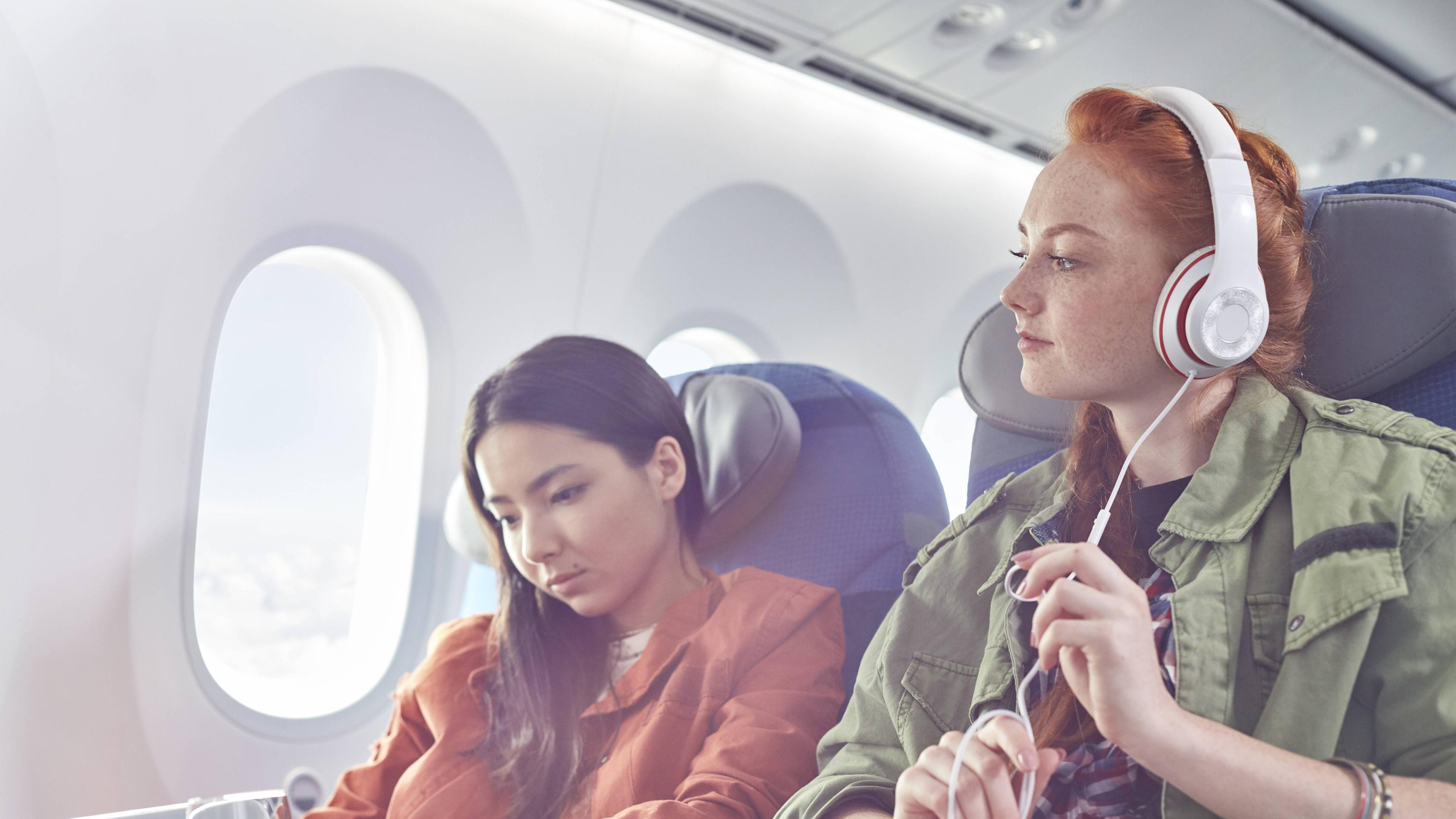 Mädchen hört im Flugzeug Musik