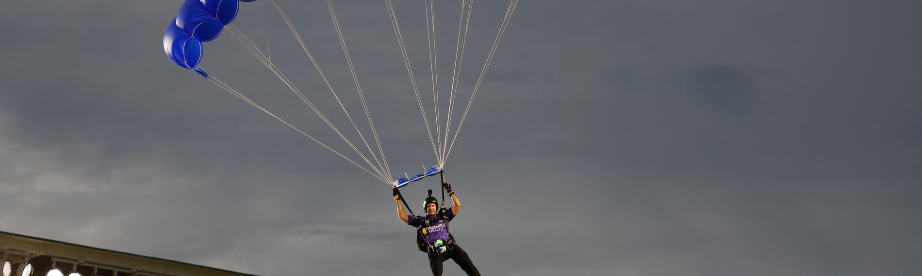 Mann fliegt mit einem Fallschirm in ein Football-Stadion.