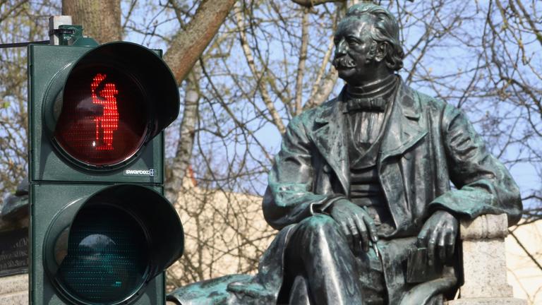 rotes Ampelmännchen mit dem Abbild des Schriftstellers Theodor Fontane vor seinem Denkmal