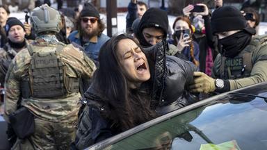 ICE-Agenten in Minneapolis, USA, verhaften am 13. Januar 2026 eine Frau, die vermeintlich die Straße blockiert haben soll.