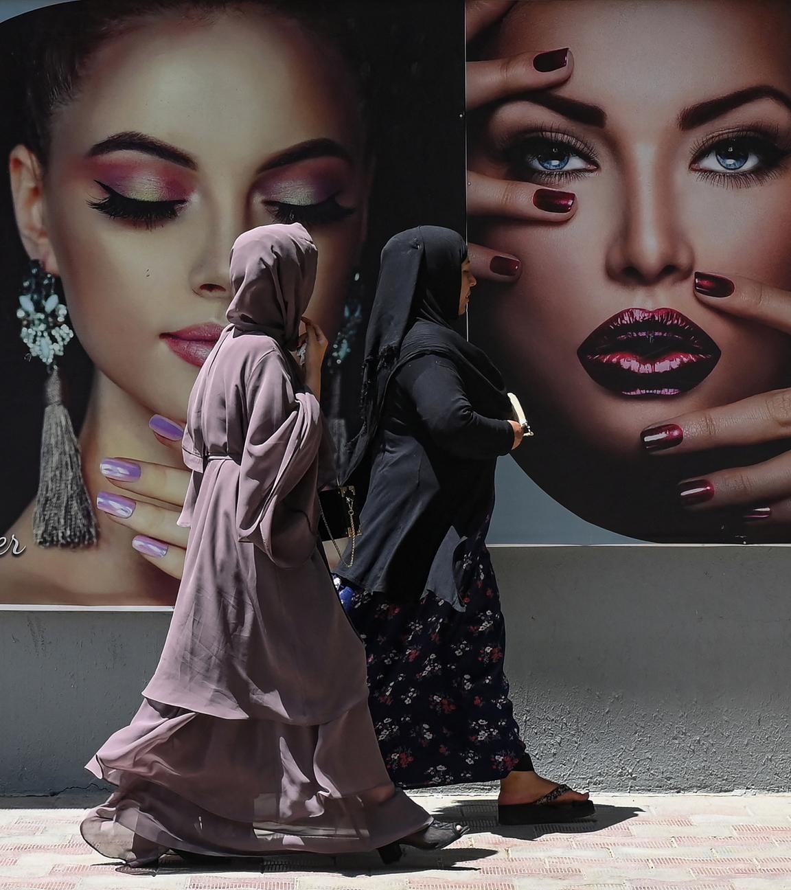 Afghanische Frauen laufen an einer Werbetafel vorbei
