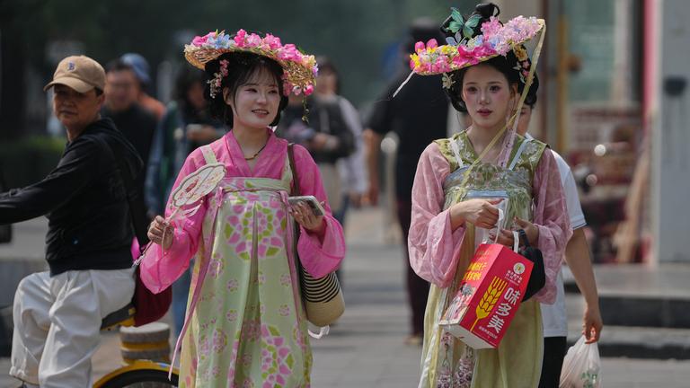 Zwei Frauen in traditionellen chinesischen Kostümen laufen durch Peking. 