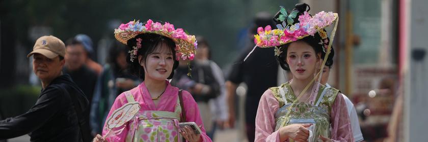 Zwei Frauen in traditionellen chinesischen Kostümen laufen durch Peking. 