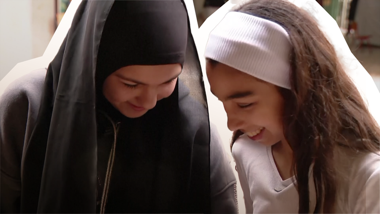 Zwei lächelnde Mädchen vor unscharfem Hintergrund