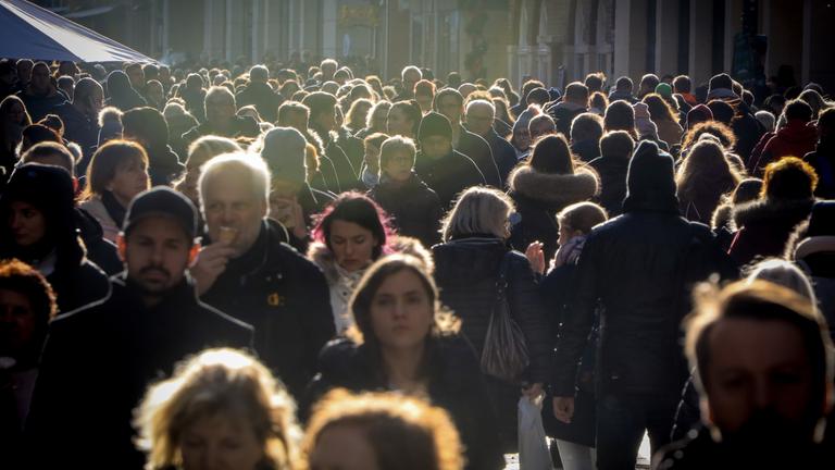 Viele Menschen in der Abendsonne in einer Fußgängerzone.