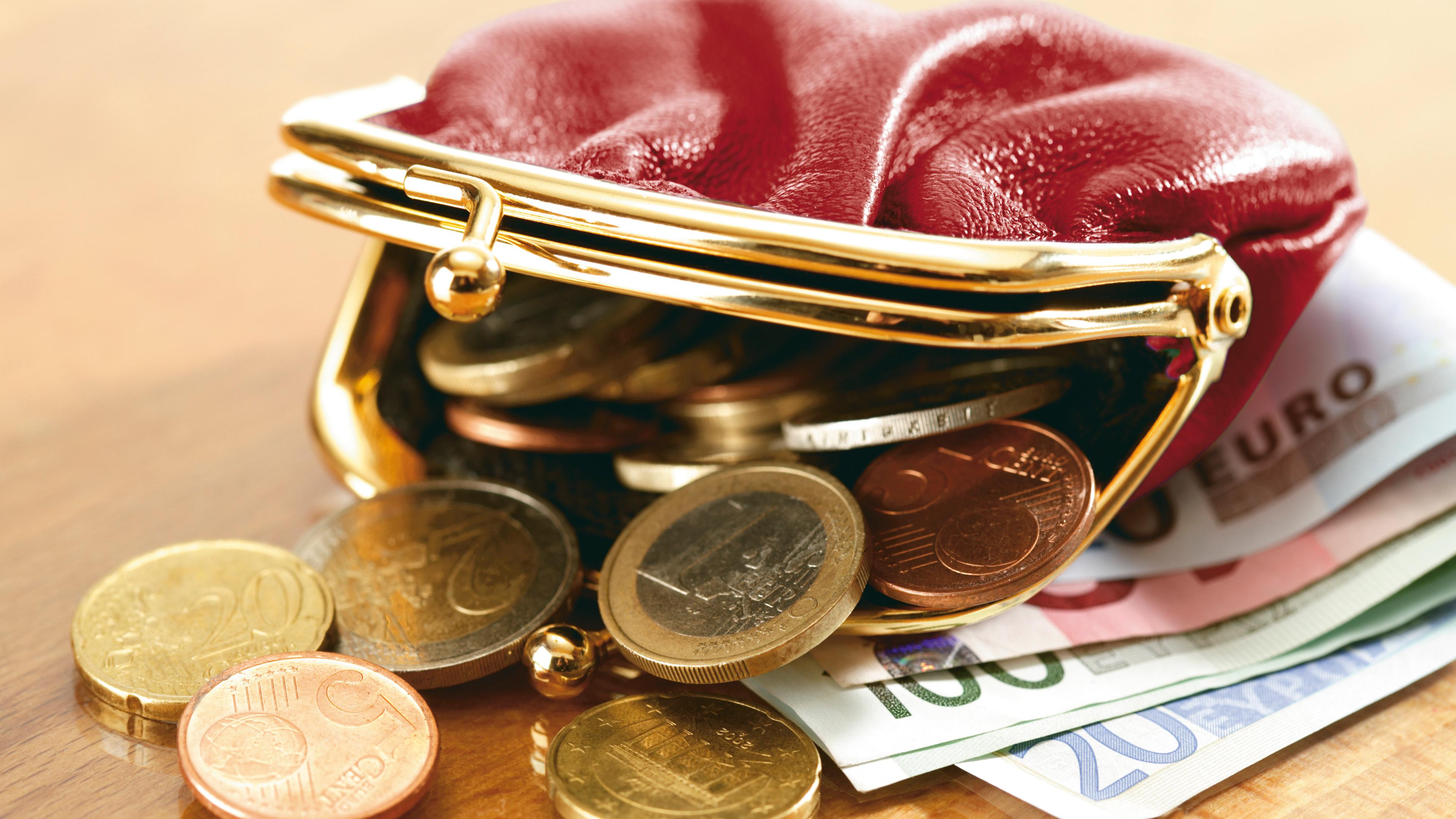 Eine offene Geldbörse, aus der Geld quilt.