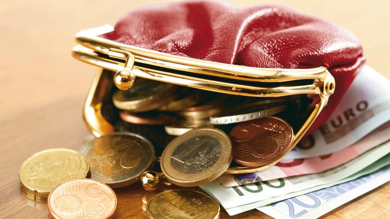 Eine offene Geldbörse, aus der Geld quilt.