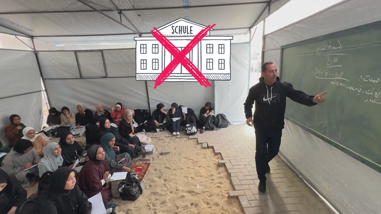 Schulkinder sitzen auf einem Boden in einem Zelt, vorne ein Lehrer mit Tafel. 