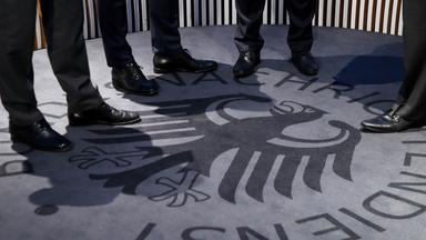 Männer stehen auf einem Teppich mit dem Logo des Geheimdienstes BND.