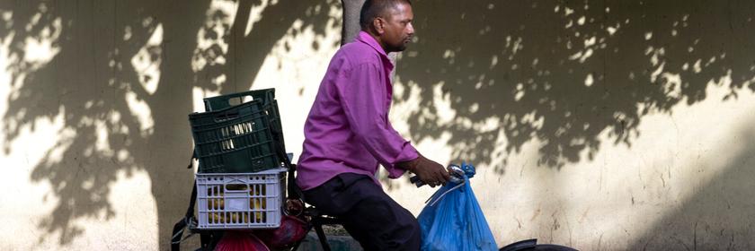 Ein Mann fährt auf seinem Fahrrad und transportiert darauf mehrere Tüten und Kisten.