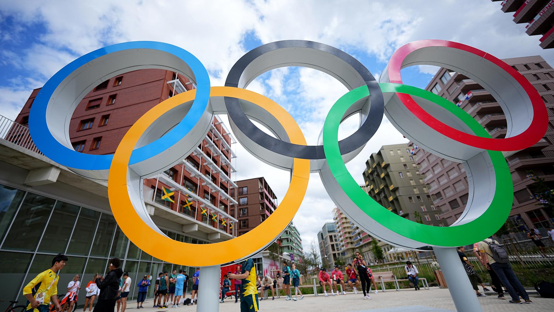 Olympishce Ringe, darin verschiedene Fotos von antiker Spielstätte, Eiffelturm, antiker Abbildung, olympisches Feuer