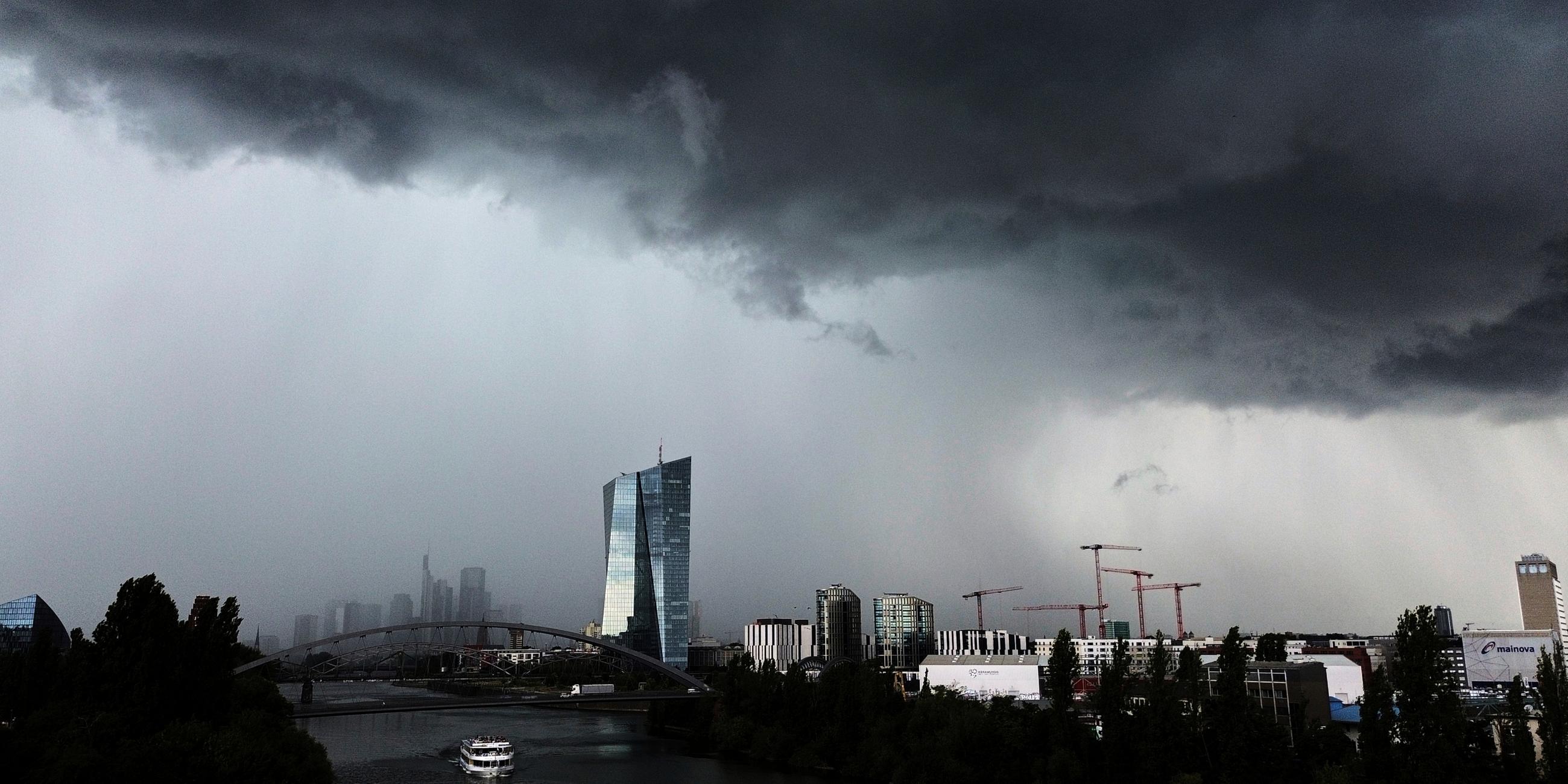 Dunkle Wolken ziehen über die Europäische Zentralbank, rechts, und die Gebäude des Bankenviertels während eines Gewitters in Frankfurt, Deutschland.