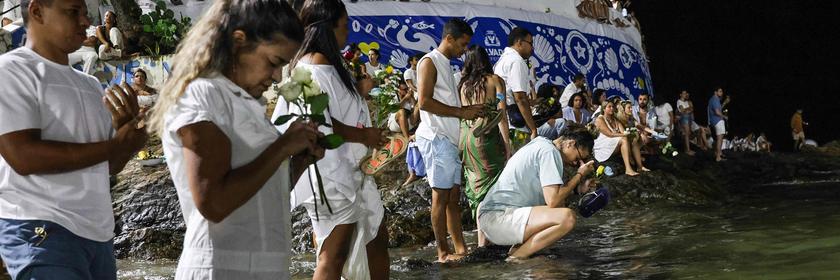 Gläubige stehen am 2. Februar in Salvador mit kleinen Geschenken, Kerzen und Blumen im flachen Wasser im Meer. Sie möchten damit für Schutz, Glück und Segen für das Jahr bitten. 