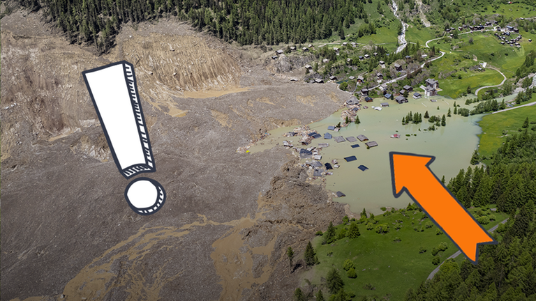 Eine Luftaufnahme zeigt ein von Schutt und Wasser begrabenes Dorf.