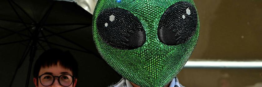 Eine Person trägt eine Glitzer-Alien-Maske. 