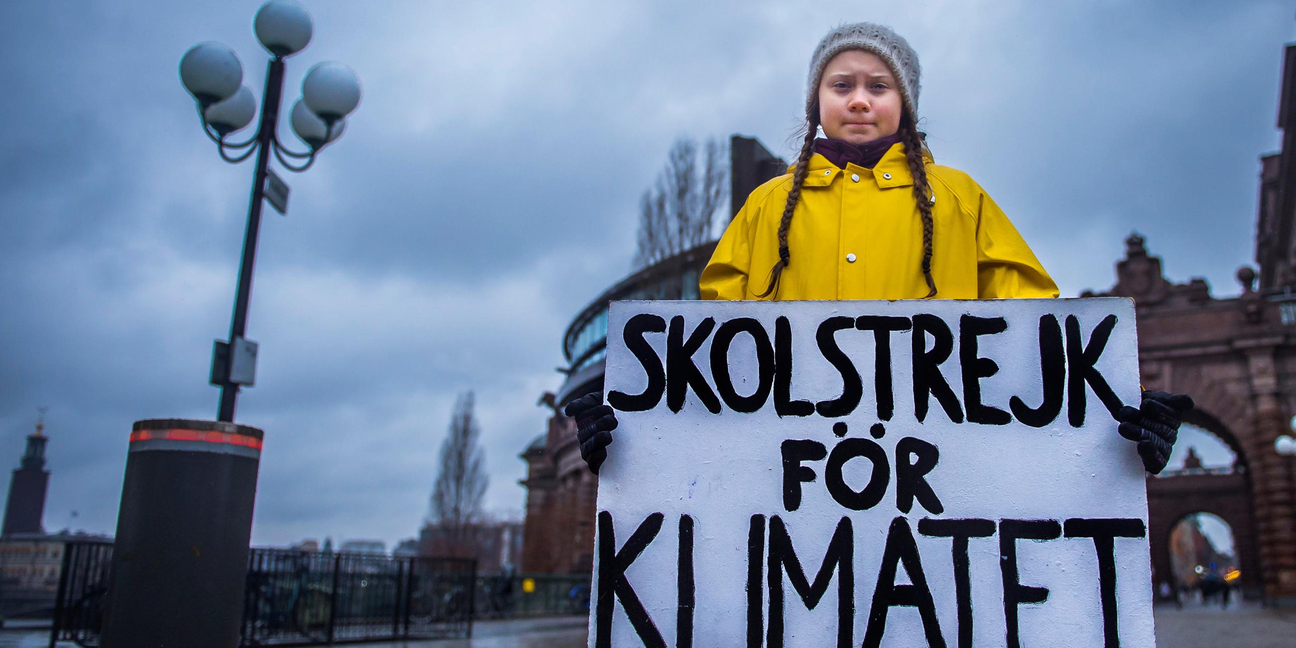 Greta Thunberg steht mit einem Schild vor dem schwedischen Parlament.