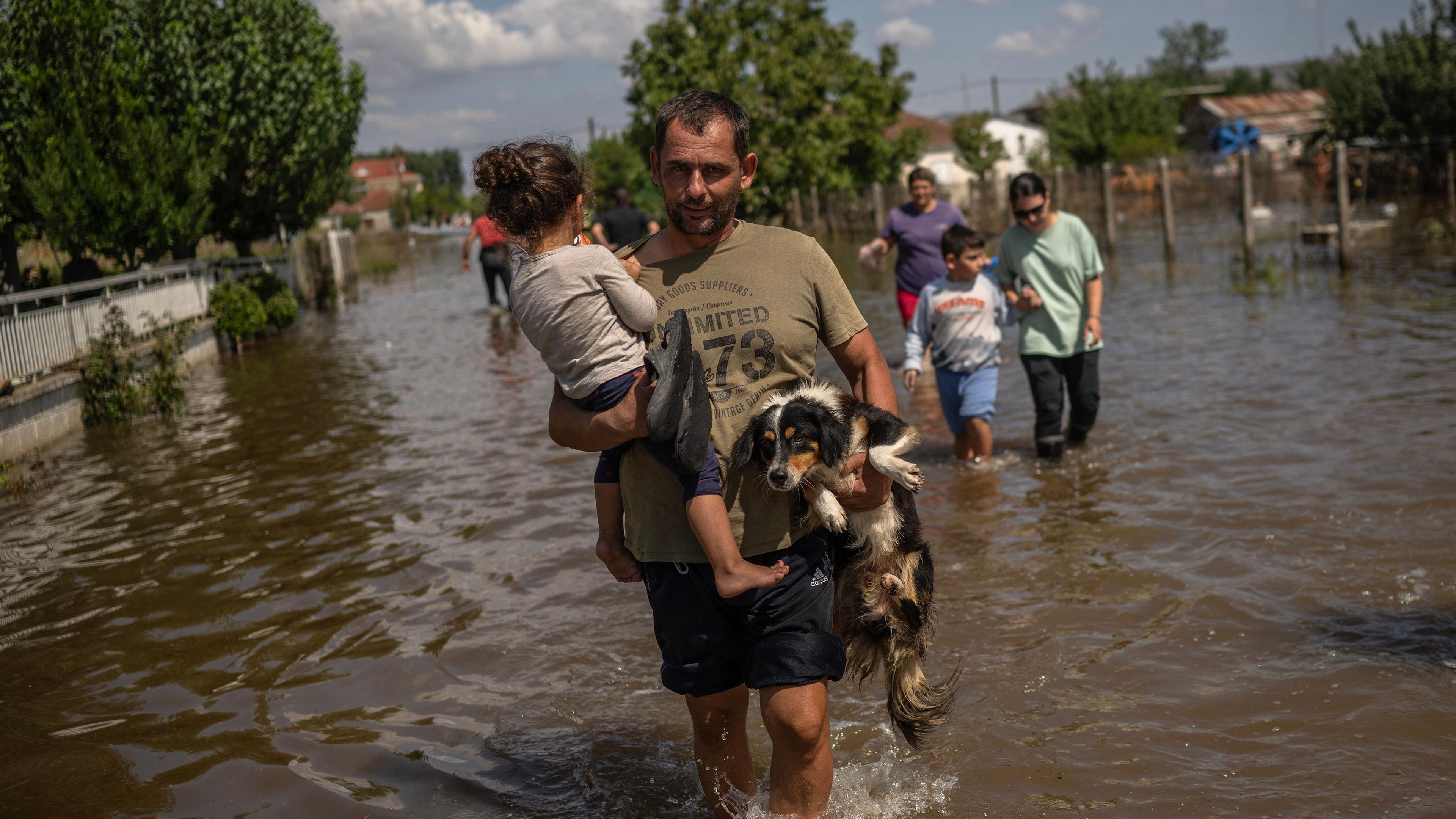 Griechenland Überschwemmungen: Vater trägt Kind und Hund durchs Wasser