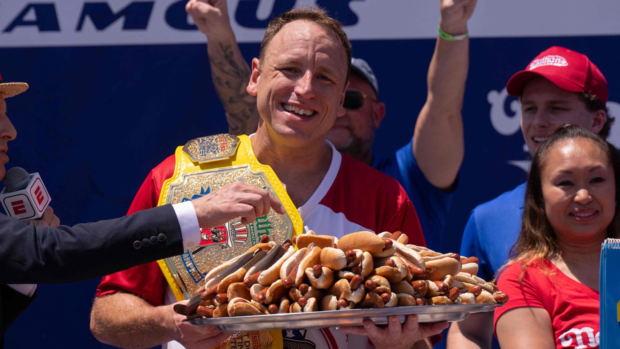 Ein Mann hält einen großen Teller voll Hotdogs in den Händen.